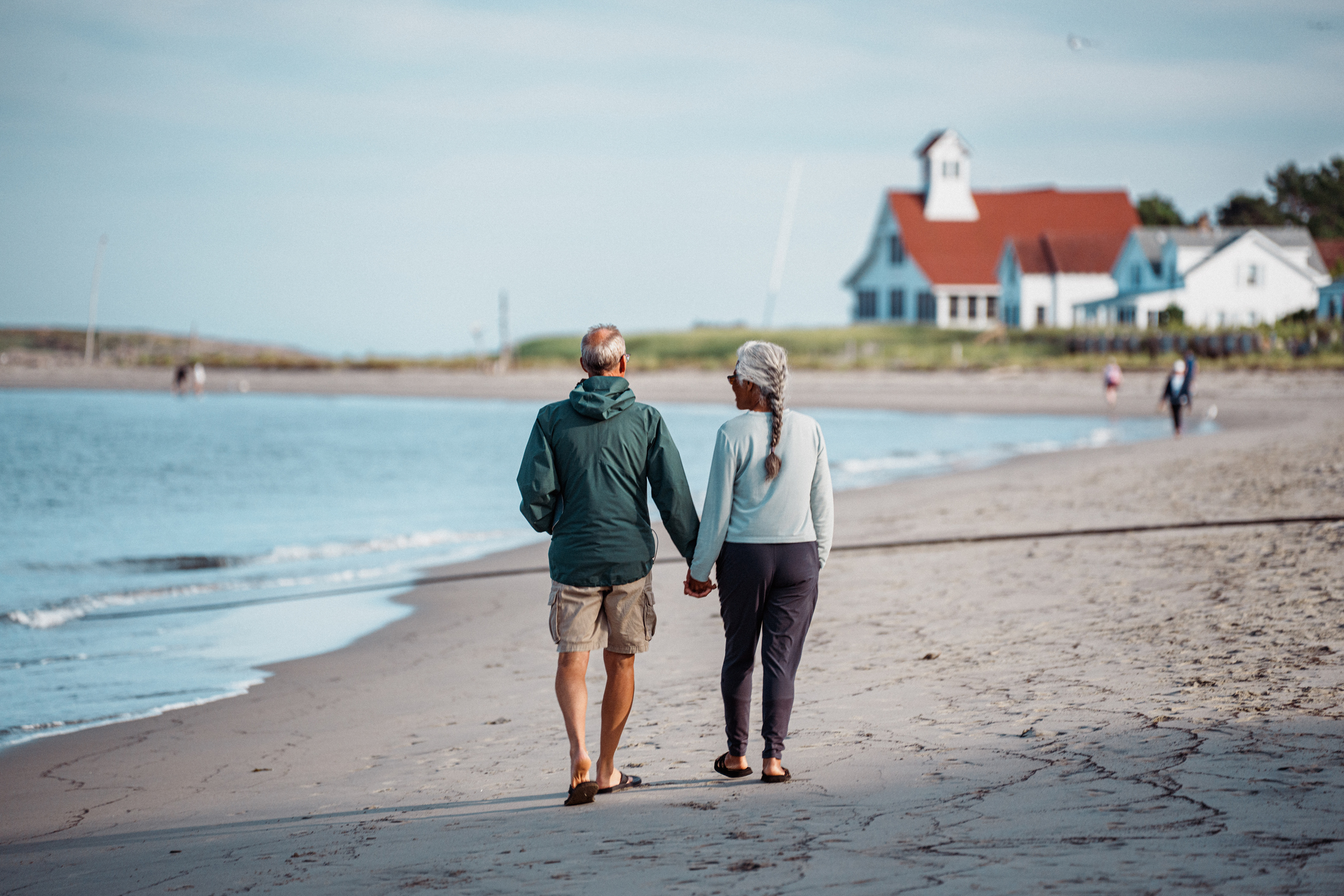 Retired Senior Couple Walking Hand in Hand Along the Beach in Coastal Maine