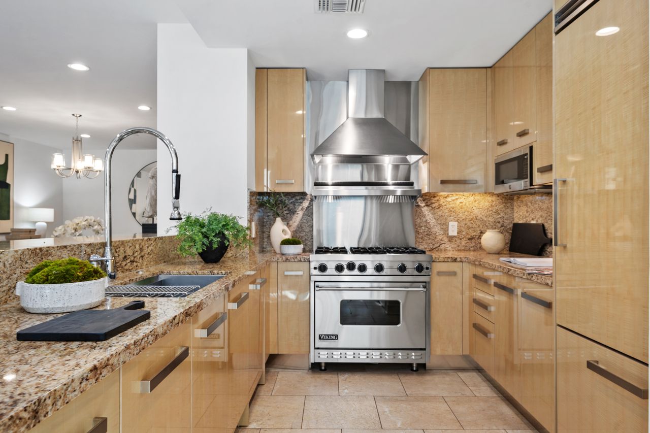 Gourmet chef's kitchen at La Terrasse featuring premium Viking stainless steel range, custom Italian cabinetry, stone countertops, and a professional-grade range hood.