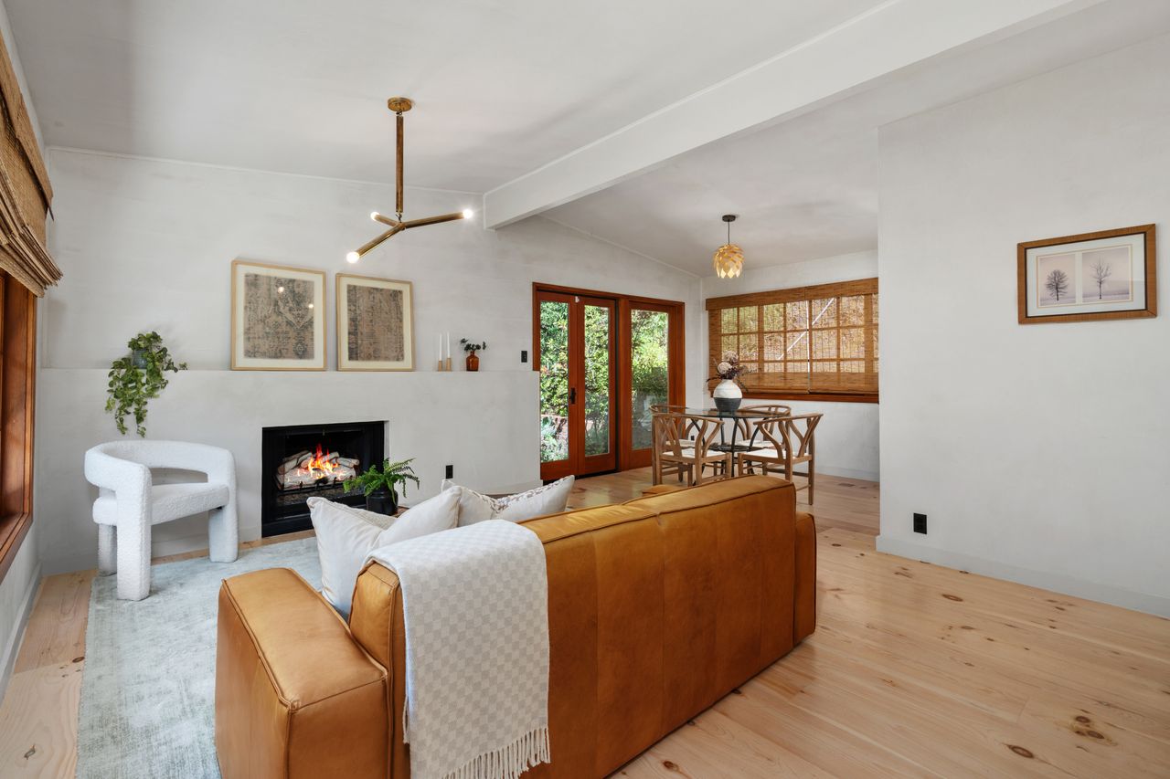 Living room featuring organic Italian plaster walls, a minimalist gas fireplace, custom wide-plank pine floors, and a leather sofa at 9667 Yoakum Drive.