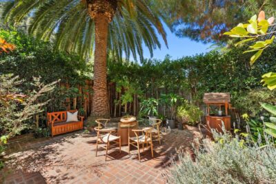 Landscaped zen courtyard with brick paving, a fountain, and mature trees in Benedict Canyon.