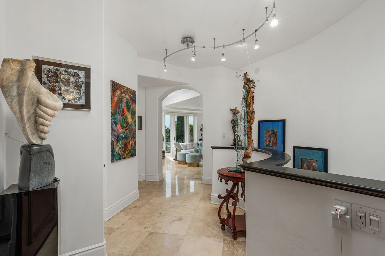 Formal gallery entry hallway with track lighting and artwork display at 137 S Spalding Dr #401