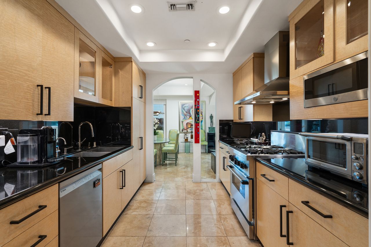 Gourmet kitchen with blonde burlwood cabinetry and black marble countertops at 137 S Spalding Dr #401