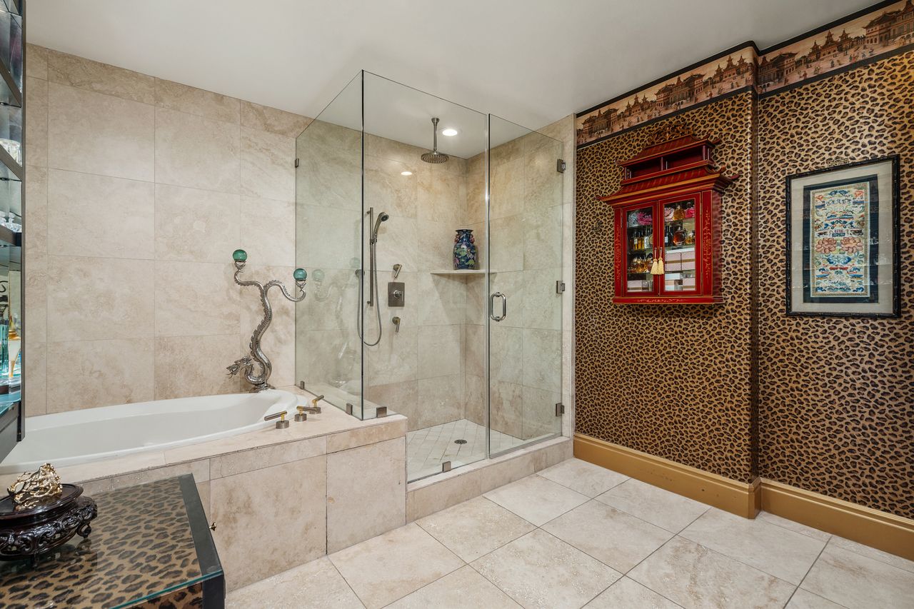 Primary bathroom spa shower and deep soaking tub surrounded by marble tile at 137 S Spalding Dr #401 Beverly Hills