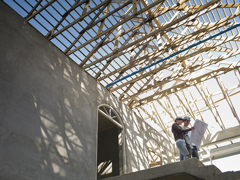 Couple looking at blueprints in house under construction