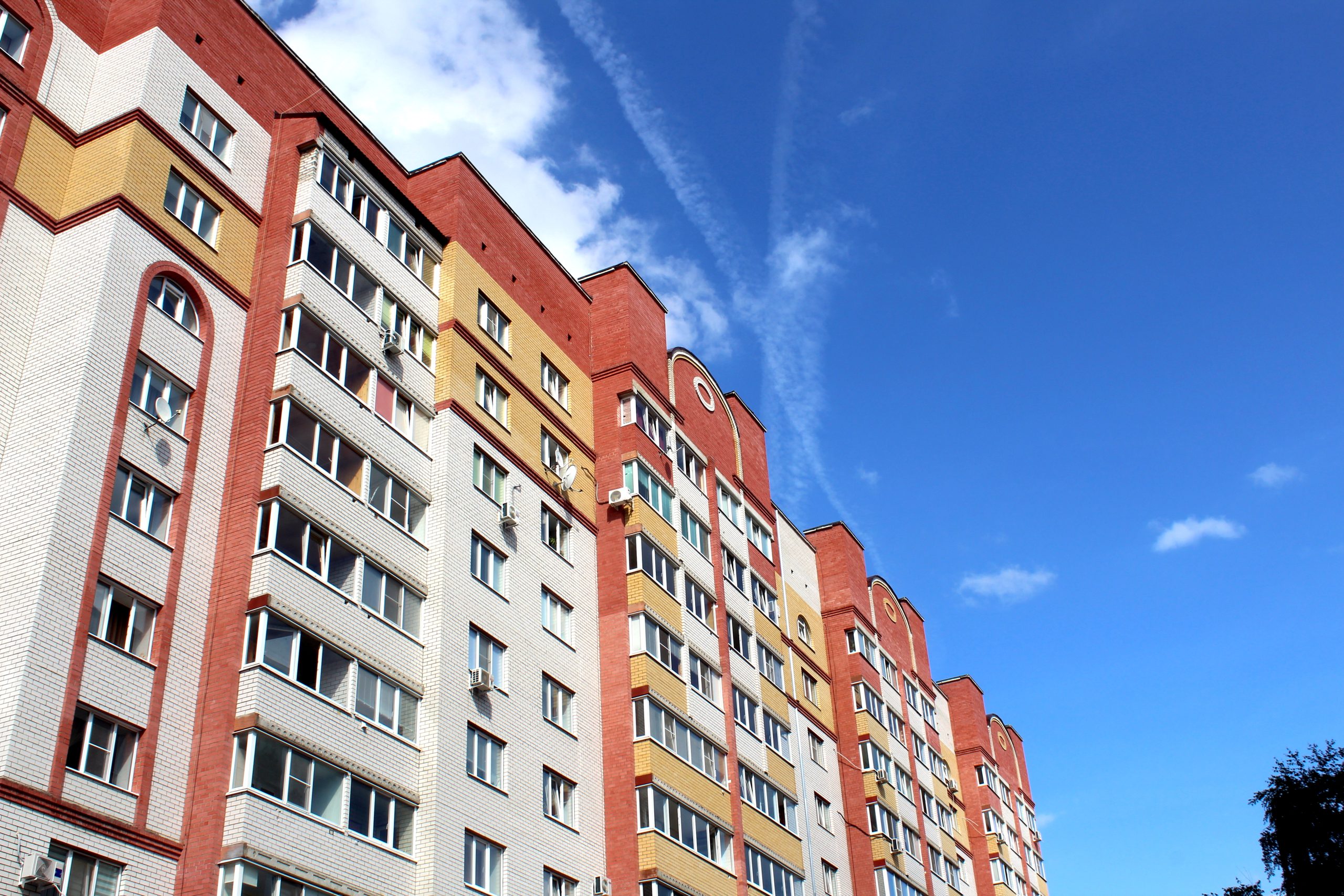 Multi-storey building with balconies against the sky on a sunny day.