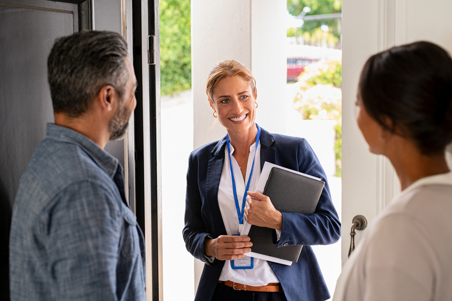 Smiling real estate agent meeting mature couple at home.