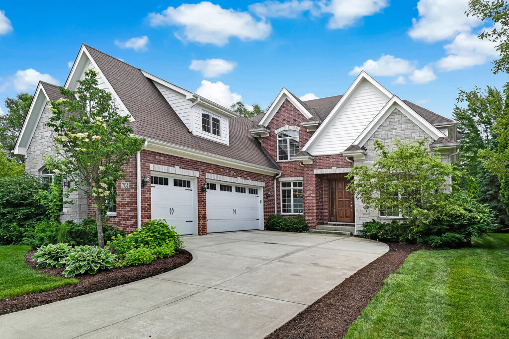 Westmont home showcasing three car garage, mature trees, and private outdoor space