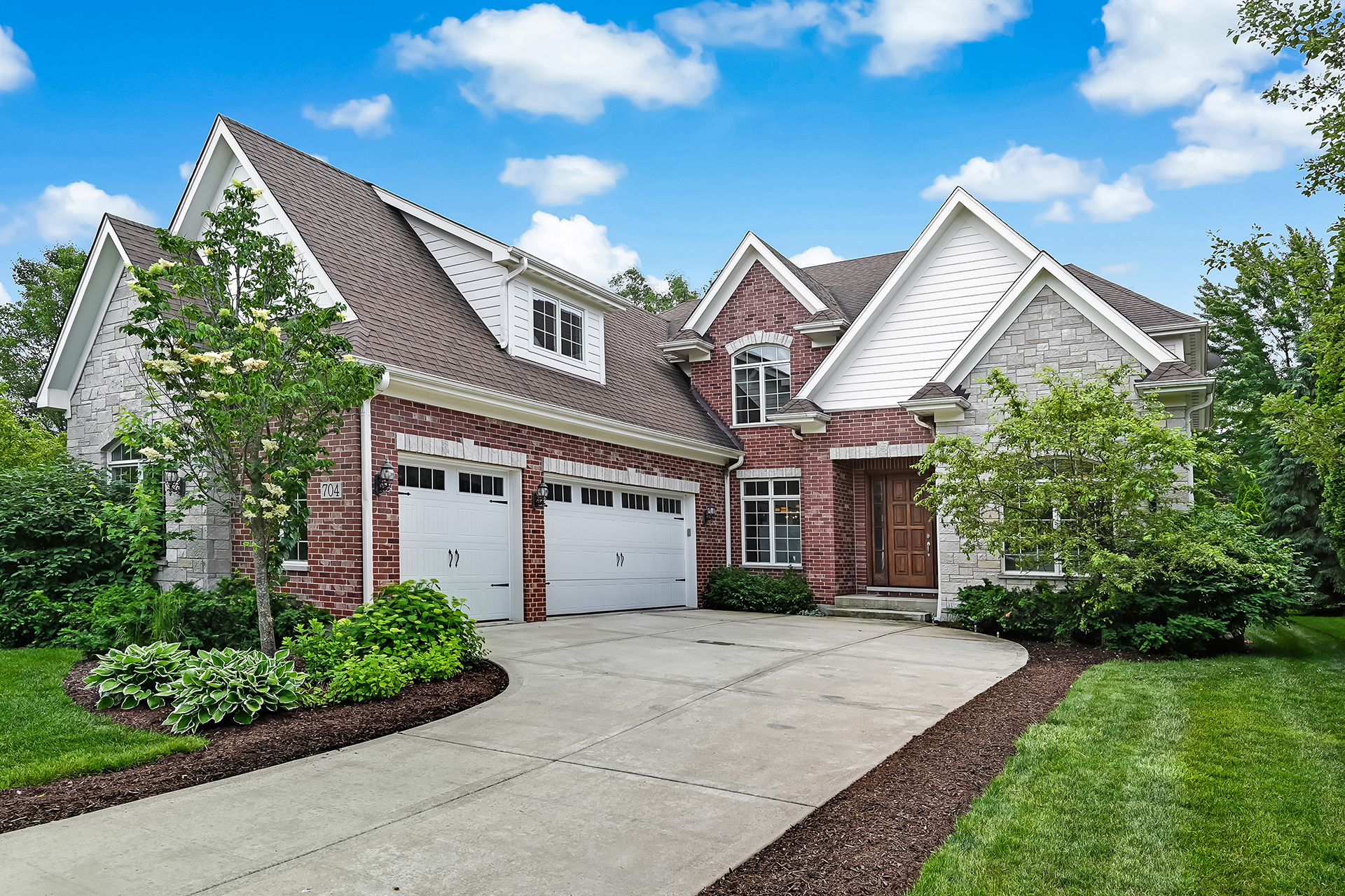 Westmont home showcasing three car garage, mature trees, and private outdoor space