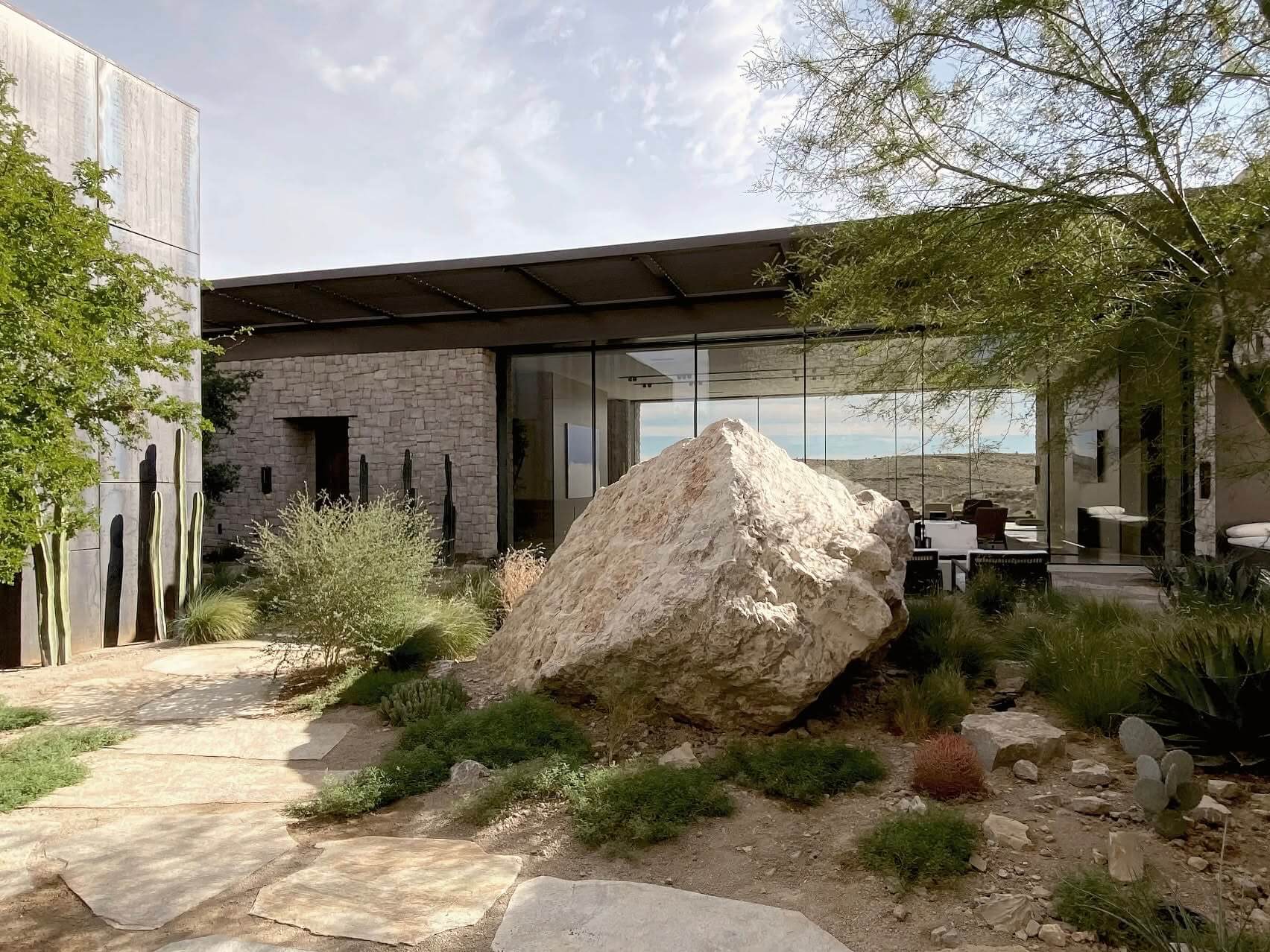 Desert landscape with a large boulder beside a modern home