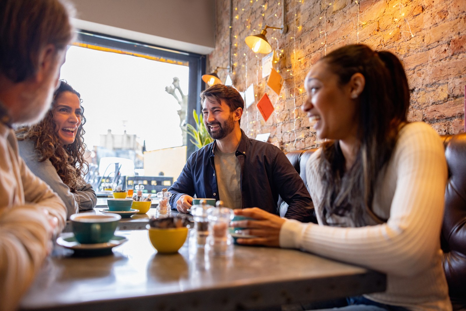 Happy friends laughing while having coffee