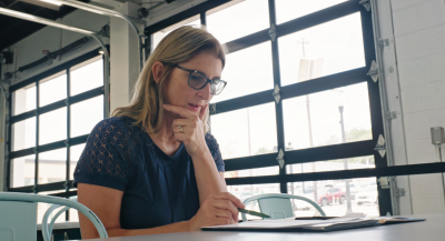 Focused real estate professional reviewing documents and planning strategically at a table near large windows.