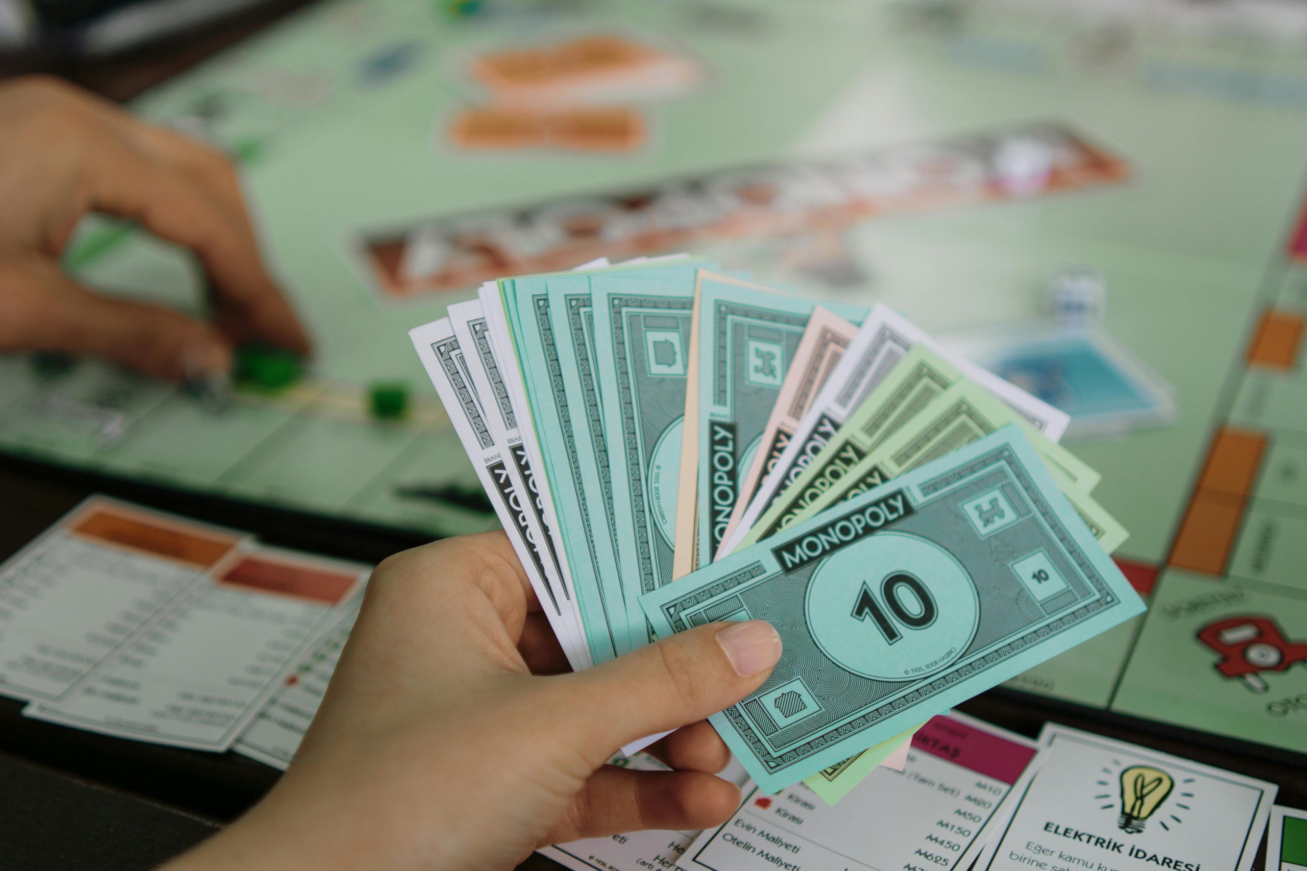 Hand holding Monopoly money representing financial decisions and negotiation strategy in real estate to include compensation