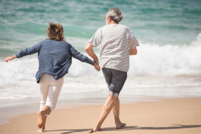 Couple jogging along the shoreline with ocean waves and a scenic coastal backdrop