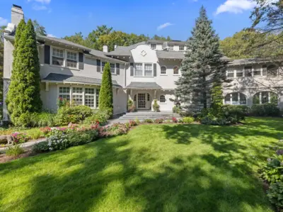 Exterior of 142 Crafts Road in Chestnut Hill, Brookline, a 1905 Chapman & Frazer Spanish Colonial estate set within mature landscaped grounds, featured as Mansion Global's Listing of the Day on April 22, 2026