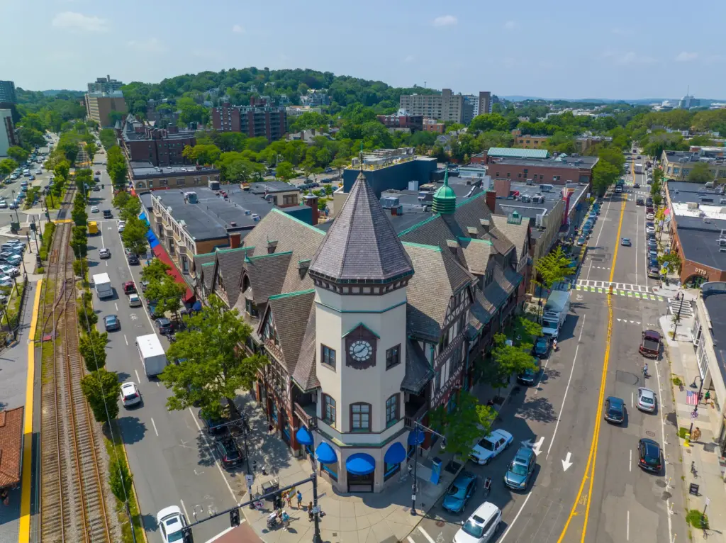 Tree-lined residential street in a Brookline MA neighborhood with historic homes and Green Line trolley tracks visible