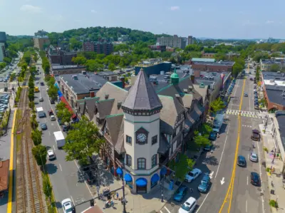 Tree-lined residential street in a Brookline MA neighborhood with historic homes and Green Line trolley tracks visible
