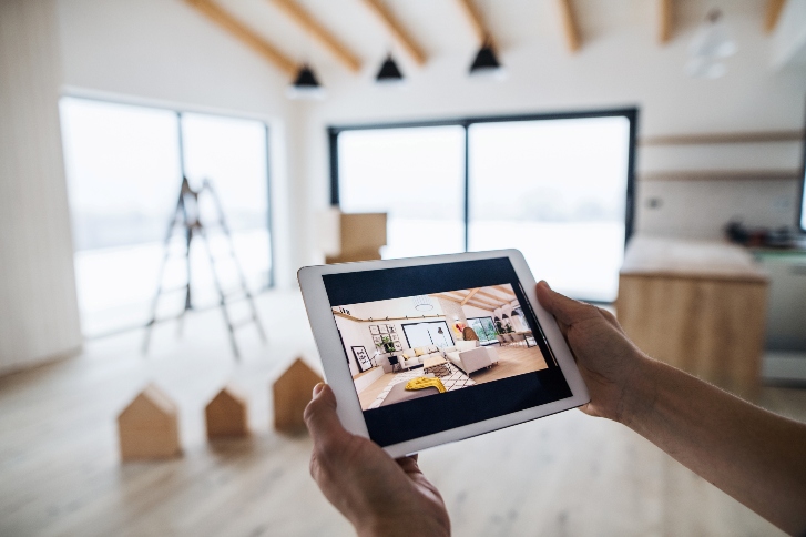 A hand holding a tablet displaying a house design