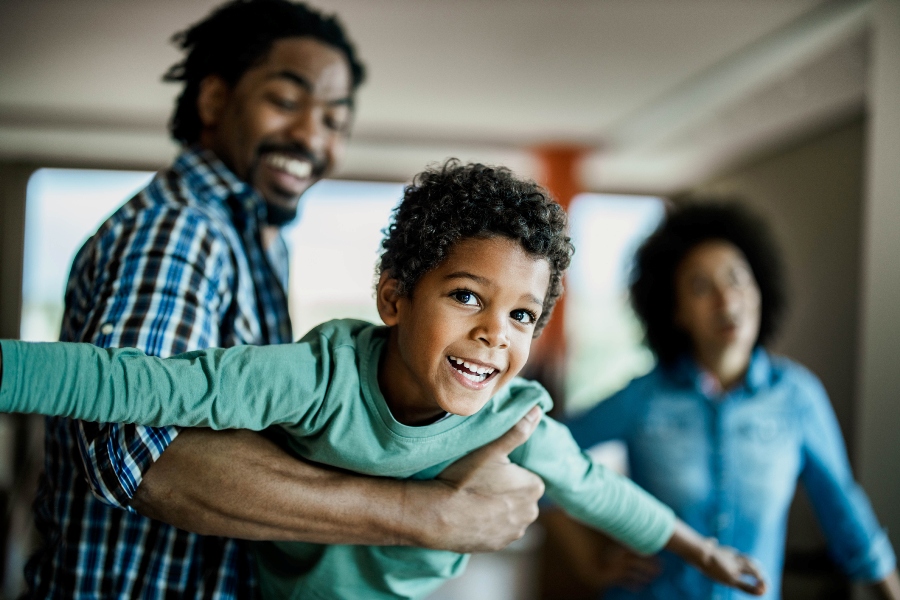Happy African American boy having fun with his father at home