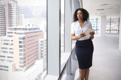 A female real estate agent standing in front of a wall to ceiling window