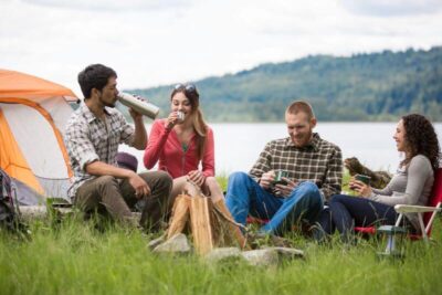 group of people camping on grass with lakeview at their back