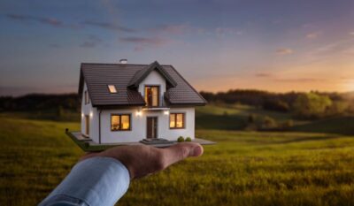 male hand showing offering a new dream house at the empty field