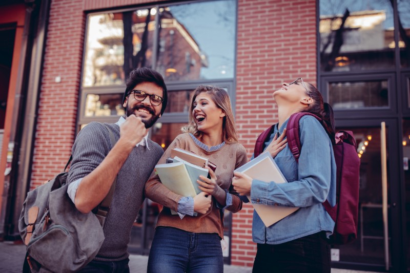 Three students laughing and rejoicing on the street