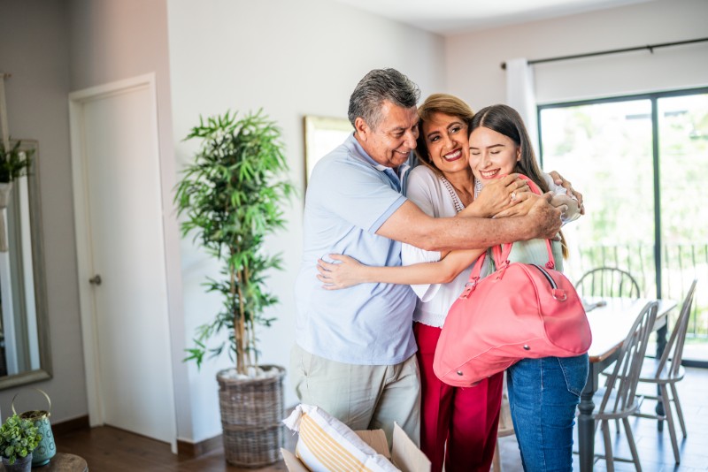 Young woman leaving parent's house and they embracing
