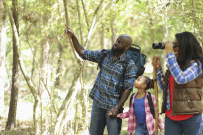 African descent family taking a summer or autumn vacation trip. They enjoy camping and hiking in the forest.