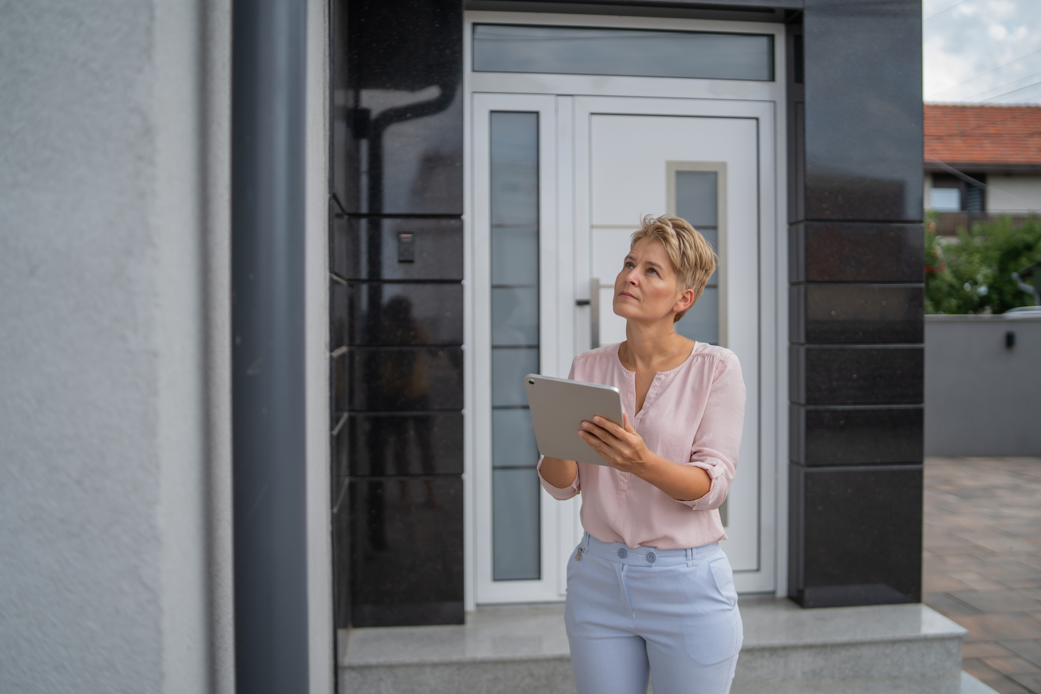 Woman appraiser examining a home's facade during an outdoor property inspection