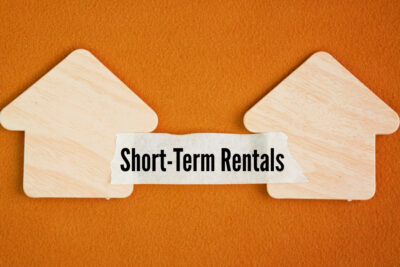 Outline of two houses with the word "short-term rental" in between the two