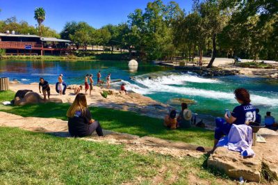 Families swimming in the San Marcos River at Rio Vista Park in San Marcos, Texas