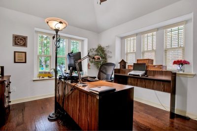 Home office with wood floors, large windows, built-in shelving, and natural light in a San Marcos TX home.