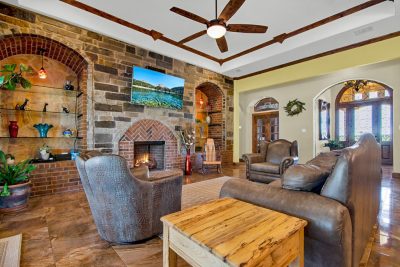 Texas Hill Country estate San Marcos TX living room with stone fireplace, wood beam ceiling, and luxury interior design