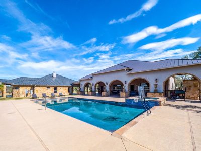 Texas Hill Country estate San Marcos TX outdoor pool area with covered patio, outdoor bar, and stone BBQ pit at 761 Allison Lane