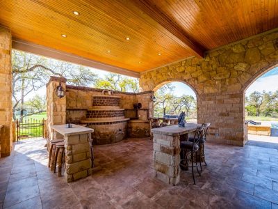 Texas Hill Country estate San Marcos TX outdoor bar with stone countertops and large stone BBQ pit