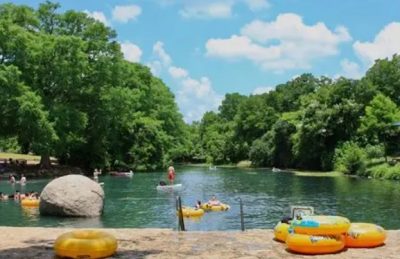 Tubers floating on the San Marcos River in San Marcos Texas using yellow tubes from the Lions Club Tube Rental