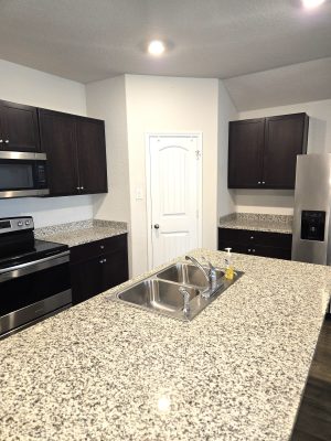 Modern kitchen featuring granite countertops, dark cabinets, stainless steel appliances, and large center island