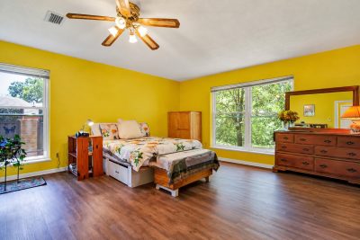 Large bedroom with bright yellow walls and flexible layout in established San Marcos residence