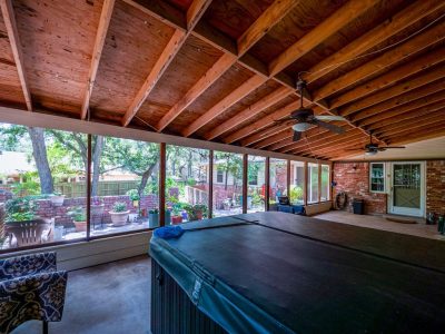 Covered screened patio overlooking shaded backyard and mature landscaping in San Marcos TX