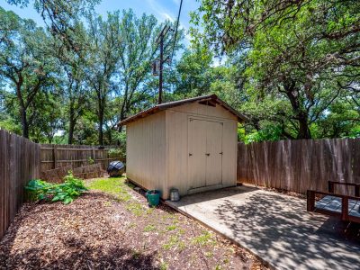 Detached storage building with additional workspace and storage capacity in shaded backyard setting