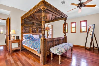 Hand-carved canopy bed in the primary suite with hardwood floors and custom woodwork