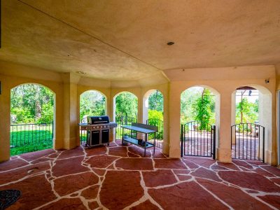 Covered outdoor entertainment patio with stone flooring, grilling area, and direct access to the backyard