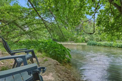 Private river access area with shaded seating along the crystal-clear waters of the San Marcos River