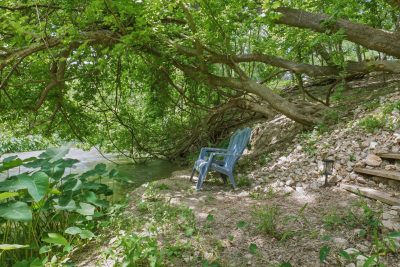 Secluded riverbank seating area beneath mature trees along the spring-fed waters of the San Marcos River