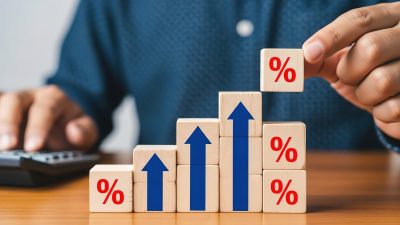 Hand Placing House Model on Increasing Interest Rate Blocks