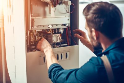 Repairman fixing a broken electric boiler or furnace
