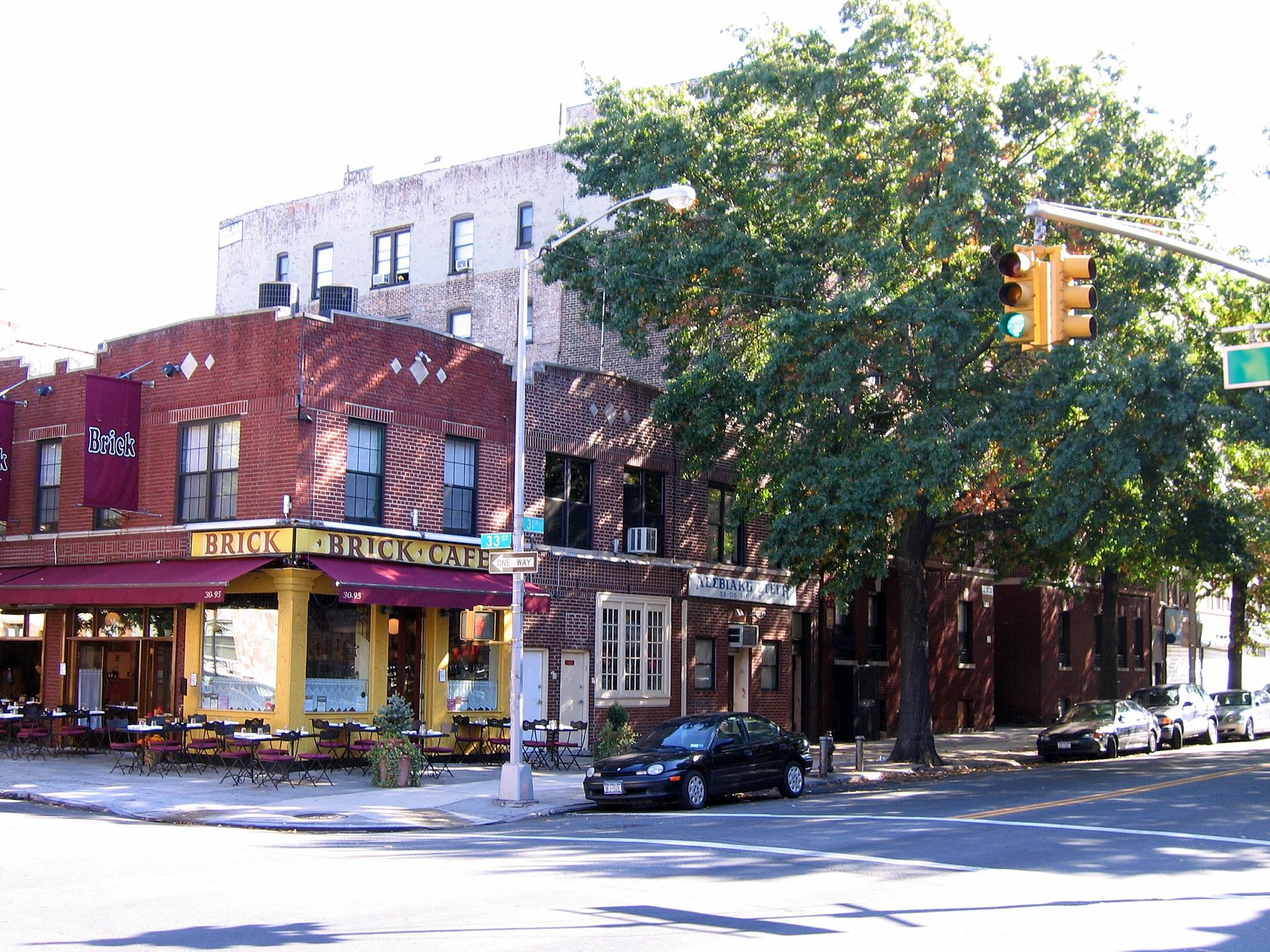 Sunny neighborhood corner with the Brick Cafe on 31st Avenue in Astoria, Queens — down payment assistance for first-time homebuyers in Queens NY
