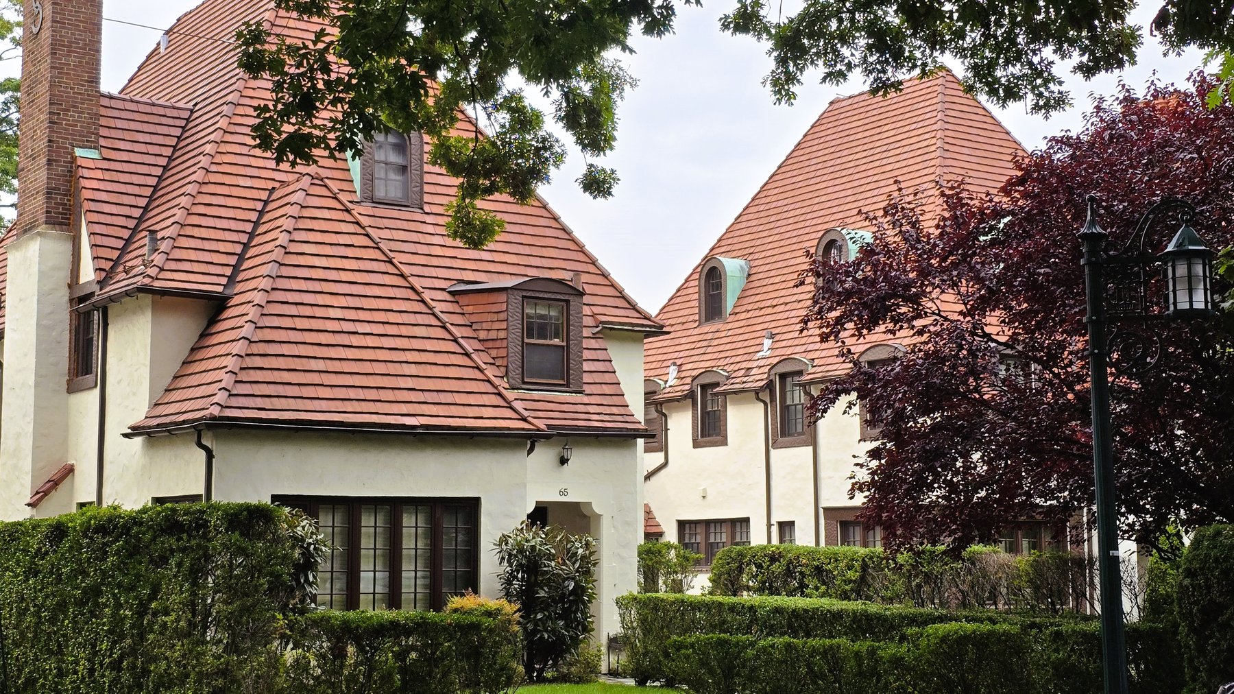 Real estate agent in Woodhaven Queens: well-kept stucco homes with tile roofs and green hedges in Forest Hills Gardens, across Forest Park from Woodhaven