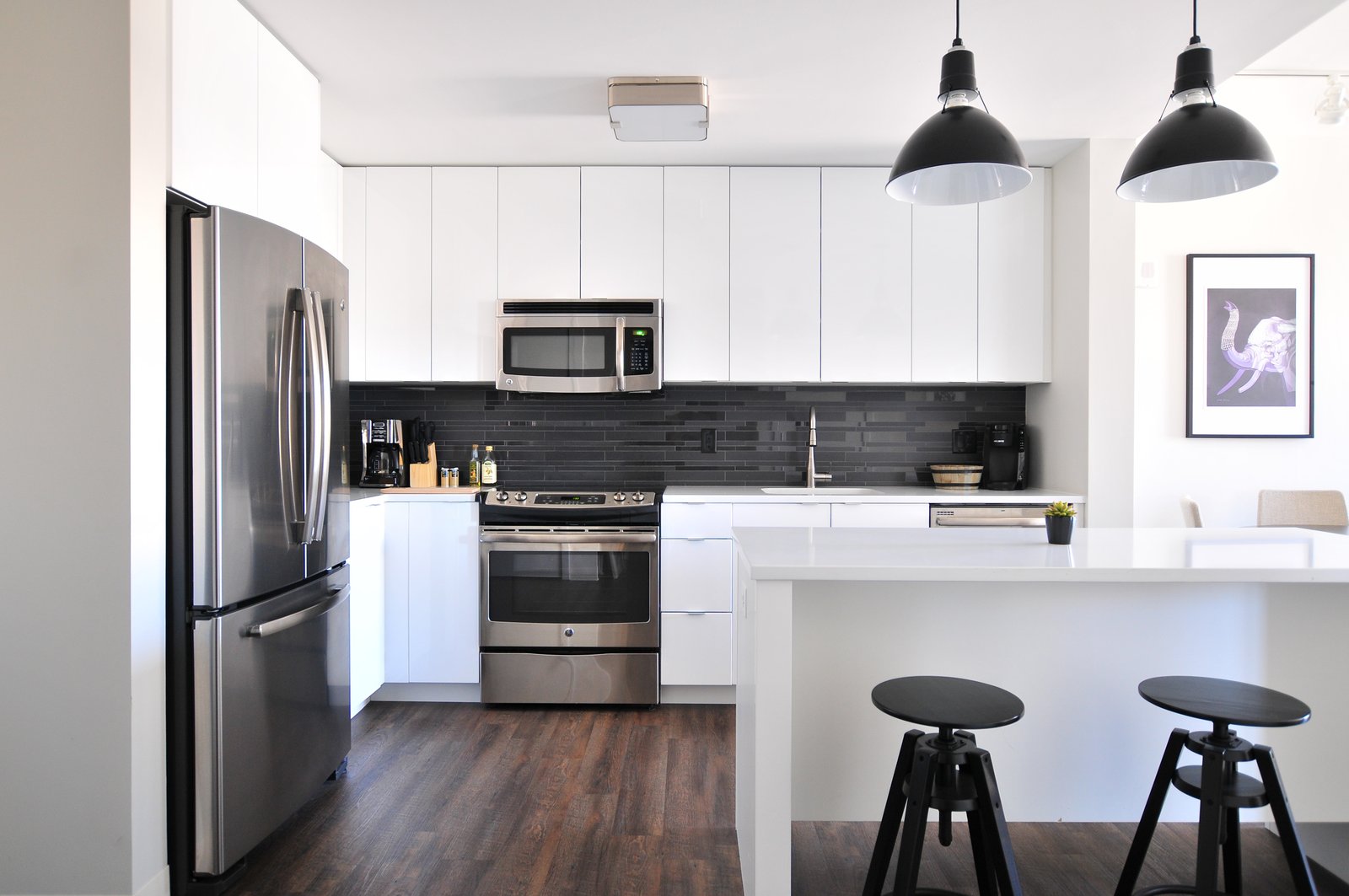 Bright modern white kitchen with an island and pendant lights, the kind of update a real estate agent in Woodhaven Queens helps sellers price and present