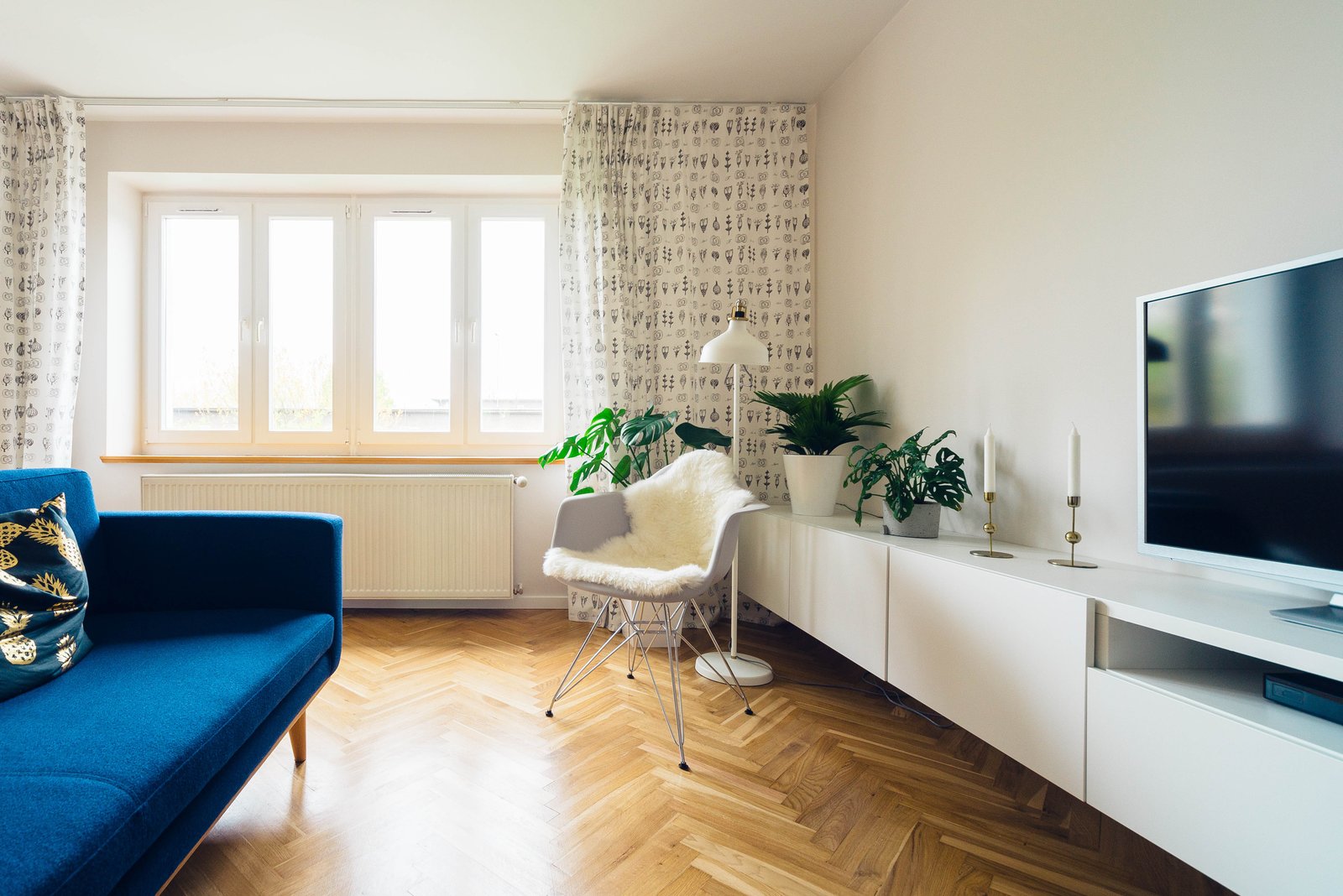 Sala moderna y luminosa con sofá azul, piso de madera en espiga y plantas: un buen agente de bienes raíces en Woodhaven Queens le ayuda a presentar así su casa